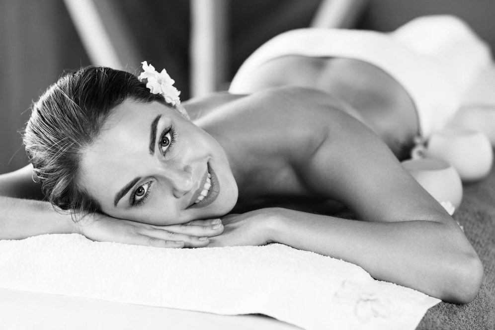 Smiling guest resting face-down on a towel, enjoying a relaxing massage treatment